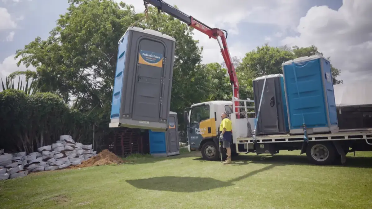 Poles and Holes delivering portable toilets by crane to a job site