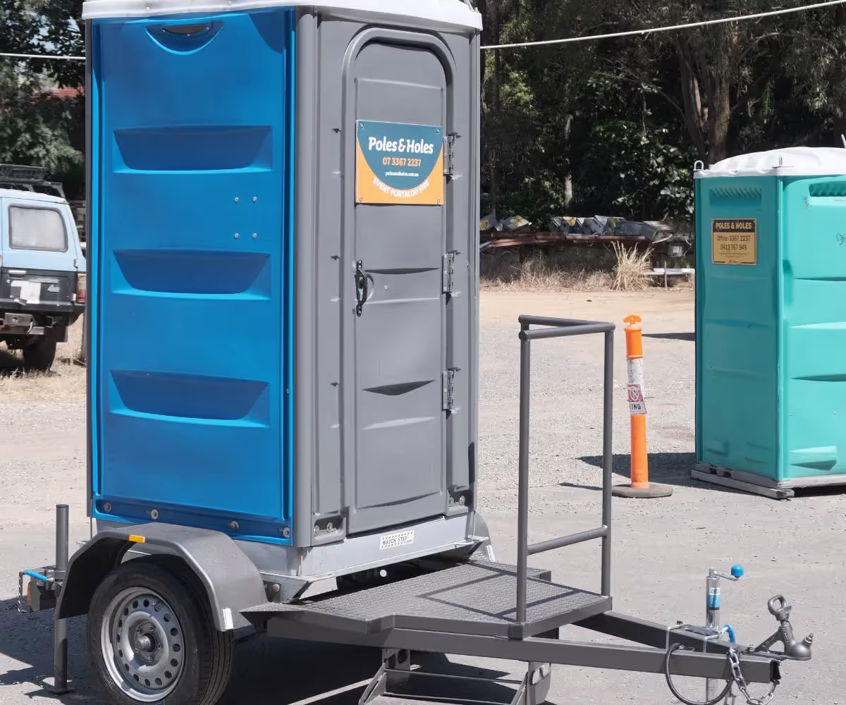 Blue trailer-mounted portable toilet with towbar, ready to tow behind a vehicle