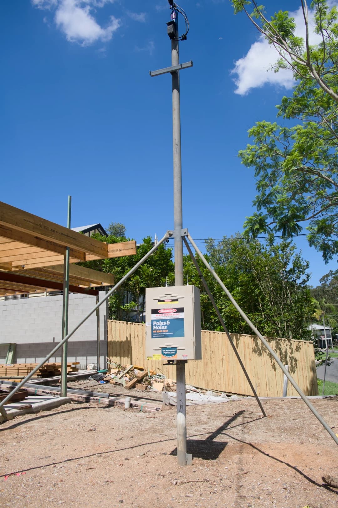 Temporary builder's power pole with metal stays on a Brisbane site