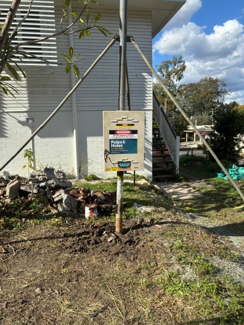 A stayed builder's power pole installed beside a Queenslander home during a residential build