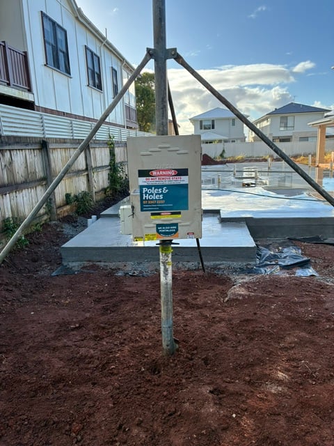 A Poles and Holes temporary builder's power pole installed with metal stays on a South East Queensland construction site